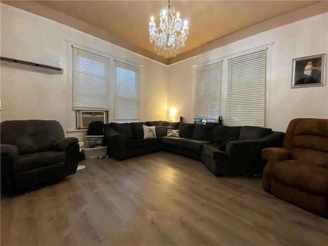 living room with a wall mounted air conditioner, hardwood / wood-style floors, an inviting chandelier, and cooling unit