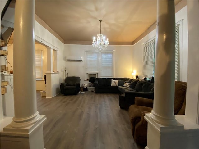 living room featuring an inviting chandelier, an AC wall unit, hardwood / wood-style floors, and ornate columns