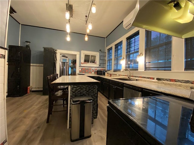 kitchen with a breakfast bar, sink, a kitchen island, light stone countertops, and hardwood / wood-style floors