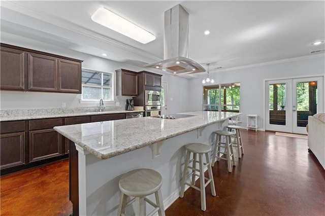 kitchen with a kitchen island, island range hood, decorative light fixtures, stainless steel appliances, and a kitchen breakfast bar