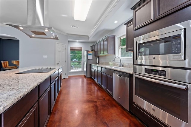 kitchen featuring island range hood, appliances with stainless steel finishes, dark brown cabinets, sink, and light stone counters