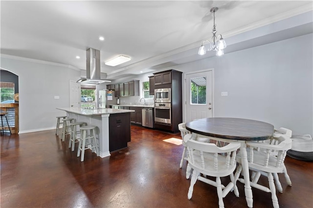 kitchen featuring appliances with stainless steel finishes, a center island, a breakfast bar, hanging light fixtures, and island exhaust hood