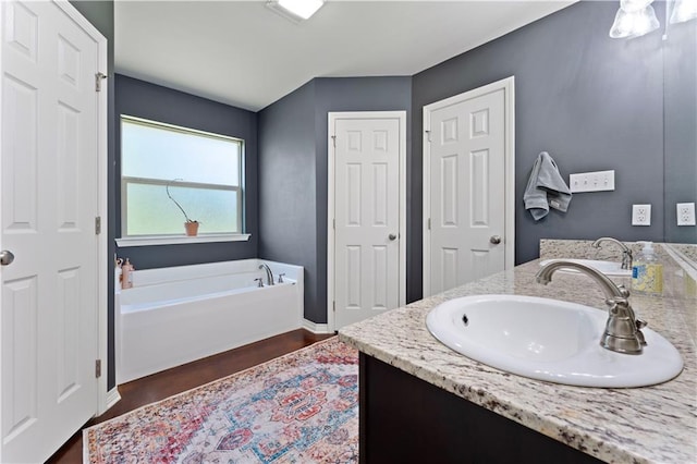 bathroom with vanity, hardwood / wood-style flooring, and a bath