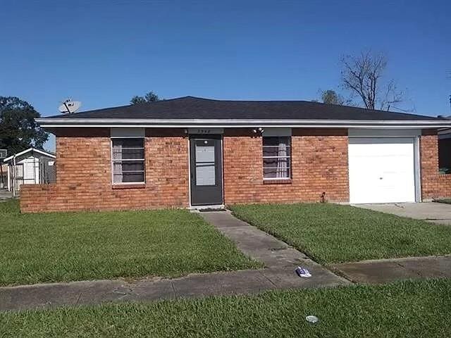 ranch-style house featuring a garage and a front lawn