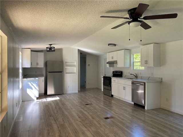 kitchen with ceiling fan, white cabinetry, stainless steel appliances, and hardwood / wood-style flooring