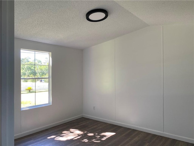 unfurnished room featuring dark hardwood / wood-style floors, a textured ceiling, and lofted ceiling