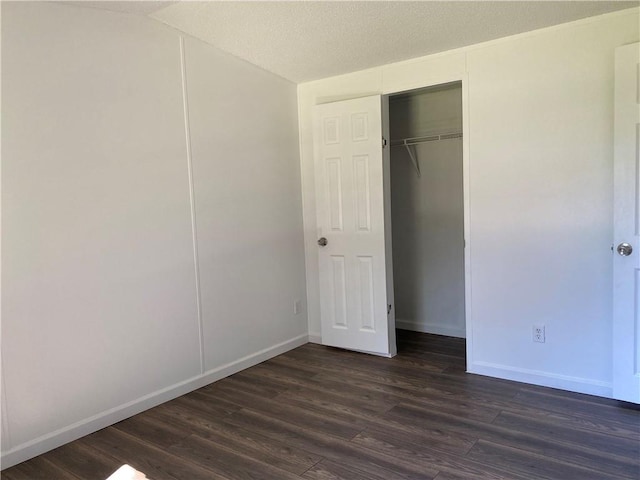 unfurnished bedroom with a closet, a textured ceiling, and dark hardwood / wood-style flooring