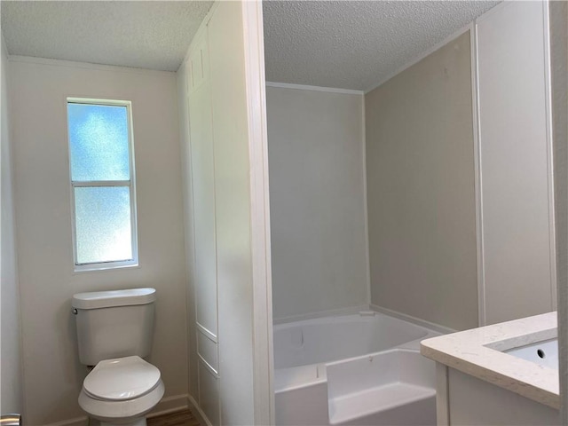 bathroom with a textured ceiling, vanity, toilet, and plenty of natural light