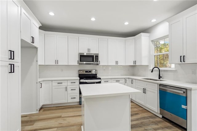 kitchen with a kitchen island, white cabinetry, appliances with stainless steel finishes, and sink