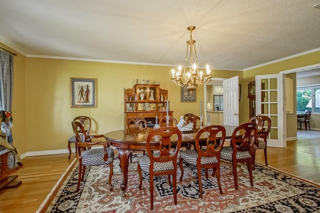 dining area featuring a textured ceiling, hardwood / wood-style floors, a notable chandelier, and crown molding