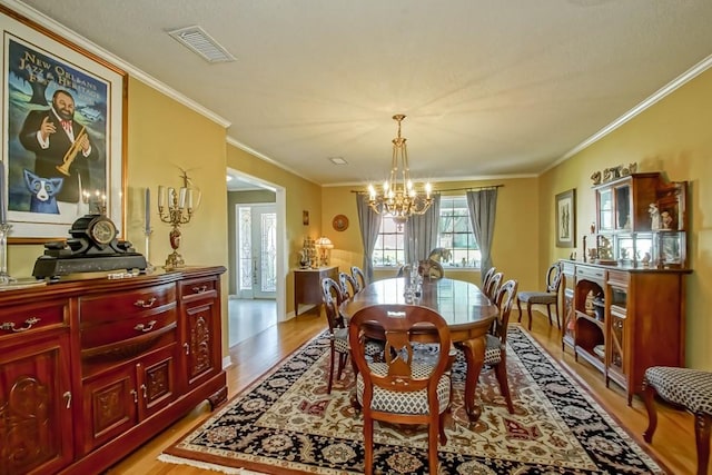 dining room featuring light hardwood / wood-style floors, a chandelier, and crown molding