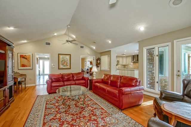 living room featuring lofted ceiling, ceiling fan, and light wood-type flooring