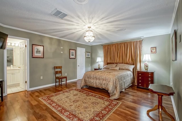 bedroom featuring ornamental molding, wood-type flooring, ensuite bathroom, and an inviting chandelier