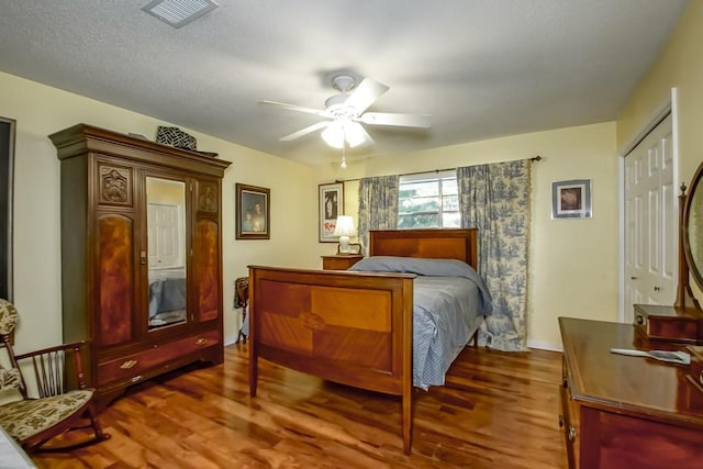 bedroom with hardwood / wood-style flooring, ceiling fan, and a textured ceiling