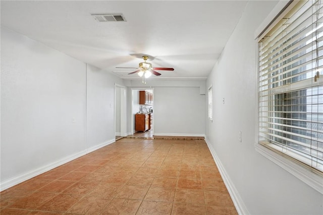 tiled empty room with ceiling fan and plenty of natural light