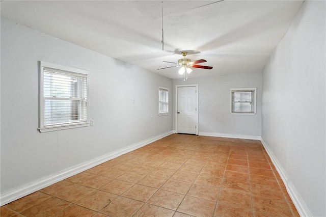 empty room with a wealth of natural light, ceiling fan, and light tile floors