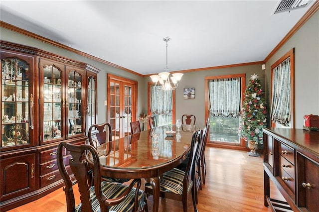 dining room with a notable chandelier, light hardwood / wood-style flooring, and crown molding