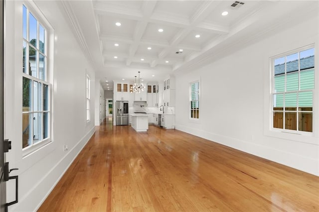 unfurnished living room with a healthy amount of sunlight, coffered ceiling, and light hardwood / wood-style floors