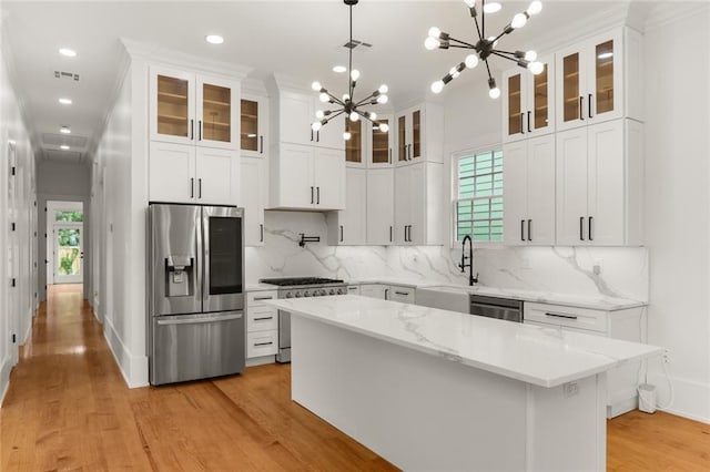 kitchen with decorative light fixtures, a chandelier, appliances with stainless steel finishes, a kitchen island, and white cabinets