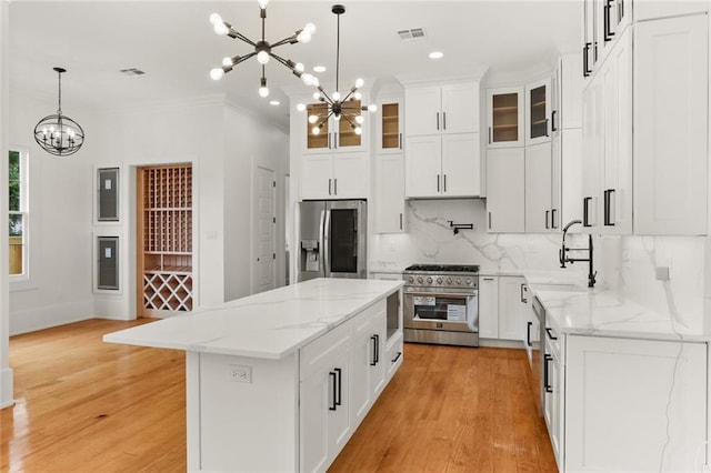 kitchen with an inviting chandelier, white cabinetry, appliances with stainless steel finishes, and a kitchen island