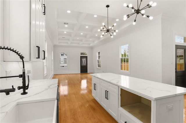 kitchen featuring pendant lighting, white cabinetry, coffered ceiling, a center island, and light stone counters