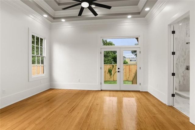 spare room featuring a raised ceiling, crown molding, french doors, and light hardwood / wood-style flooring