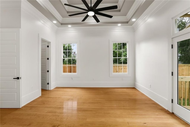 empty room featuring crown molding, ceiling fan, a tray ceiling, and light hardwood / wood-style floors