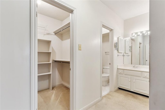 walk in closet with sink and light carpet