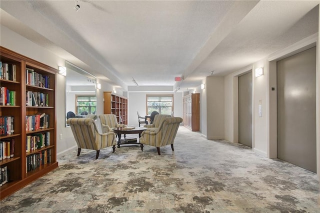 living area with elevator and a textured ceiling