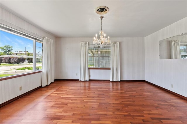 unfurnished room with hardwood / wood-style floors and a chandelier