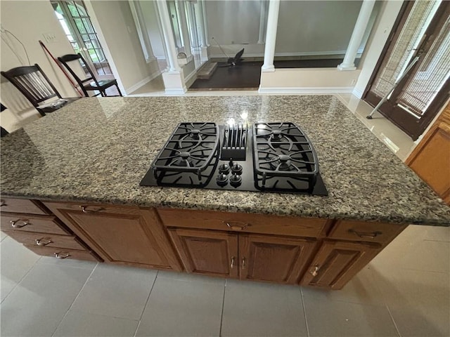 kitchen with ornate columns, black gas stovetop, and dark stone counters