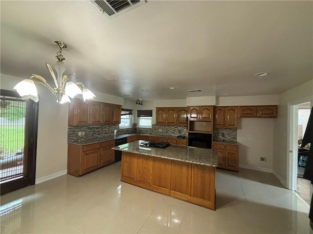 kitchen with backsplash, light tile flooring, a center island, and black oven