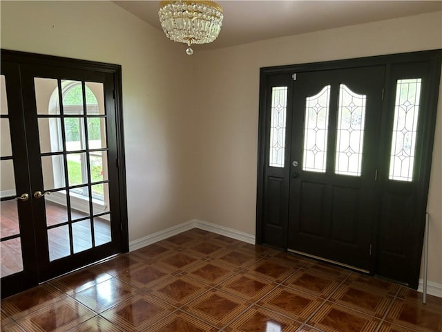 tiled foyer featuring french doors, an inviting chandelier, and vaulted ceiling