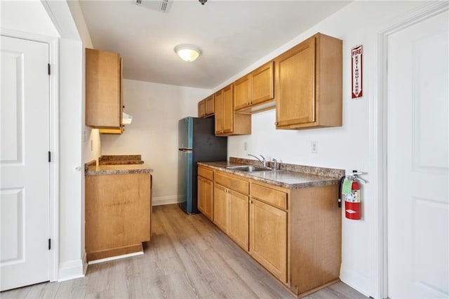 kitchen featuring black refrigerator, light hardwood / wood-style flooring, and sink