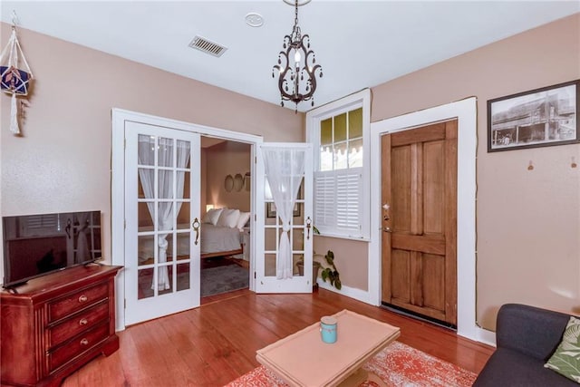 living room with wood-type flooring, french doors, and an inviting chandelier