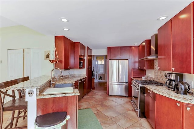 kitchen with wall chimney range hood, stainless steel appliances, sink, light tile floors, and a kitchen bar