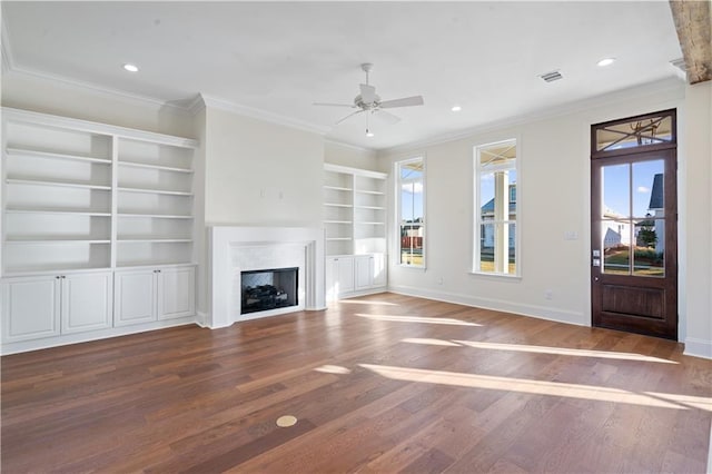 unfurnished living room featuring built in shelves, hardwood / wood-style flooring, ceiling fan, and a healthy amount of sunlight