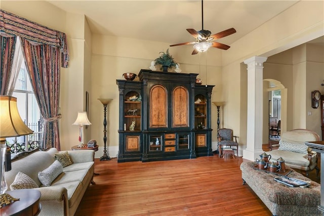 living area featuring hardwood / wood-style floors, ceiling fan, and decorative columns