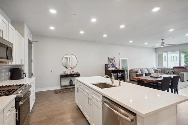 kitchen featuring wood-type flooring, a kitchen island with sink, appliances with stainless steel finishes, sink, and ceiling fan