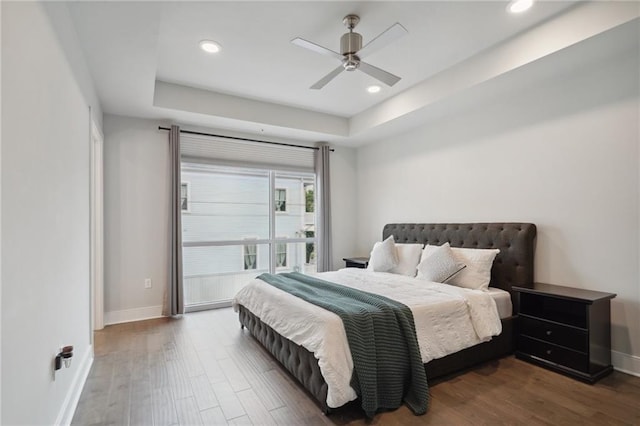 bedroom featuring wood-type flooring, ceiling fan, and a raised ceiling