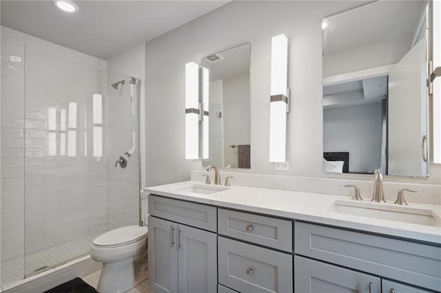 bathroom with tiled shower, toilet, dual vanity, and tile flooring