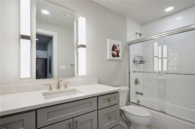 full bathroom with toilet, shower / bath combination with glass door, and vanity