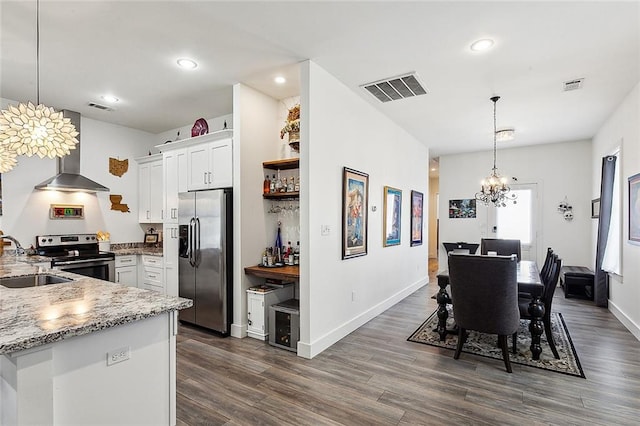 kitchen featuring decorative light fixtures, stainless steel appliances, wall chimney exhaust hood, white cabinets, and dark hardwood / wood-style flooring