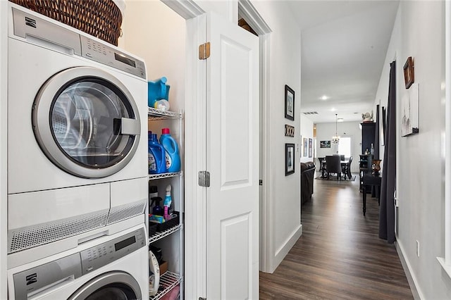 washroom featuring stacked washer and clothes dryer and dark wood-type flooring