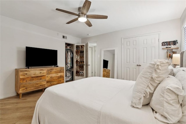 bedroom featuring wood-type flooring, ceiling fan, and multiple closets