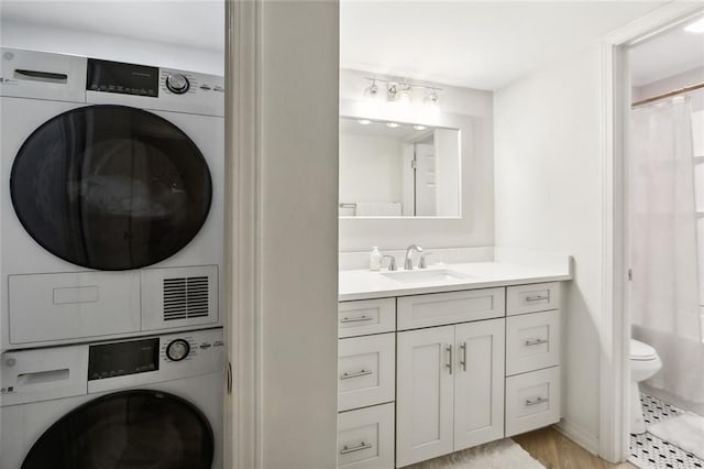 washroom featuring sink, light hardwood / wood-style flooring, and stacked washing maching and dryer