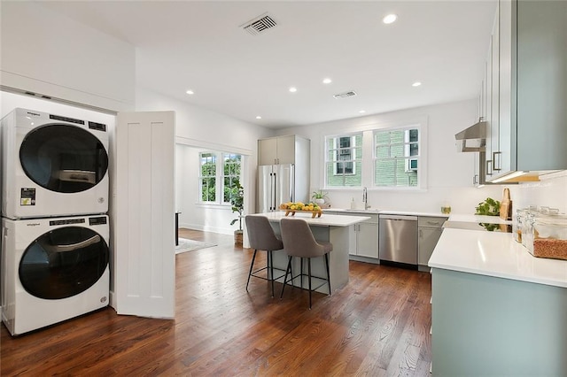 laundry area with dark hardwood / wood-style flooring, stacked washer and dryer, and sink