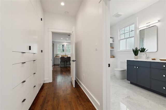 corridor featuring dark tile floors and sink