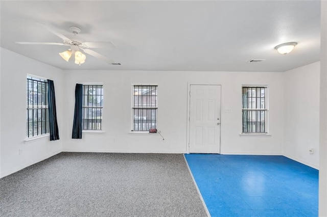 empty room with plenty of natural light, carpet floors, and ceiling fan