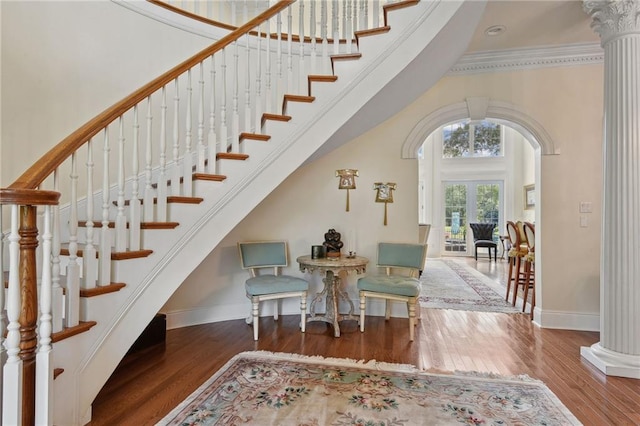 staircase with decorative columns, crown molding, and hardwood / wood-style floors